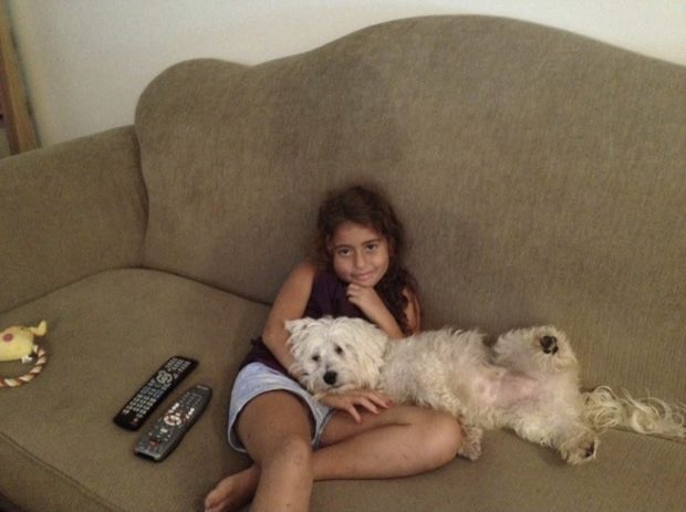 Deb as a young girl sitting on the couch with her dog Cooper